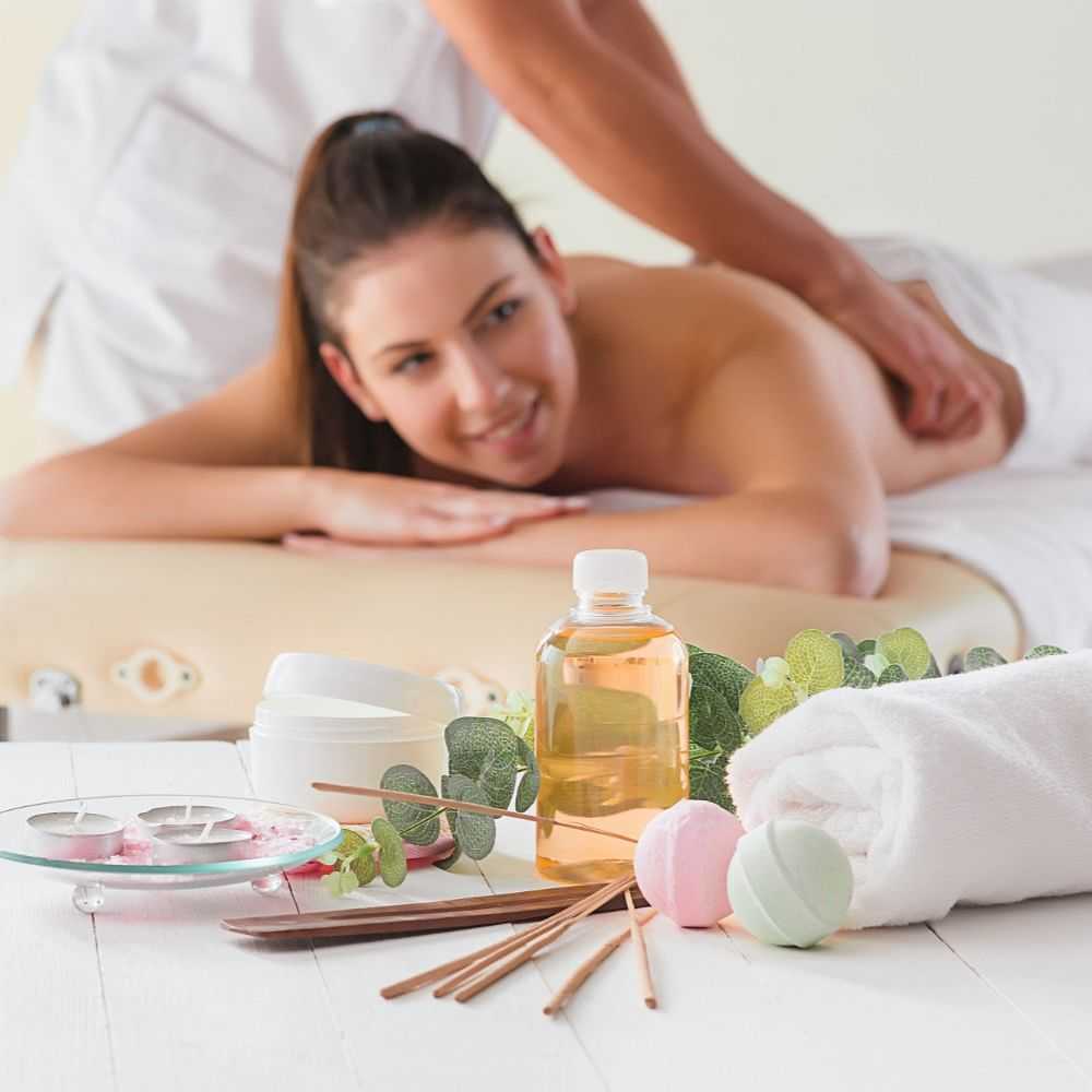 Woman receiving a relaxing back massage with spa essentials in the foreground.